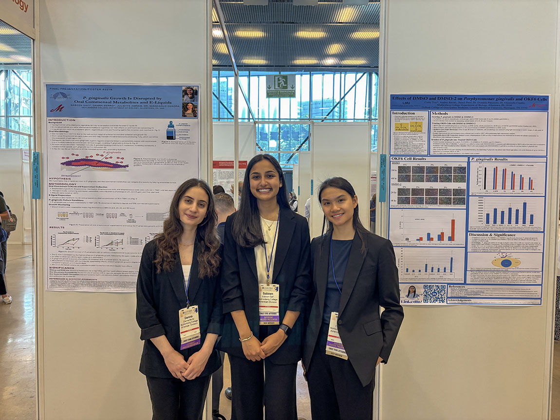 Three college students at a conference with their posters behind them